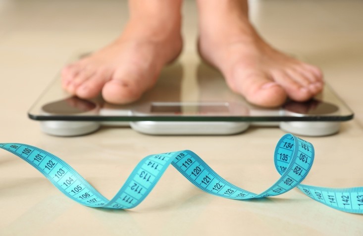 person weighing themselves on a scale measuring weight loss