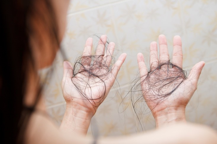 person looking at hair in their hands that has fallen out of their head