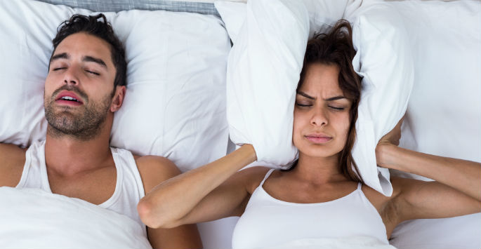 sleep apnea - woman struggling to sleep next to man snoring
